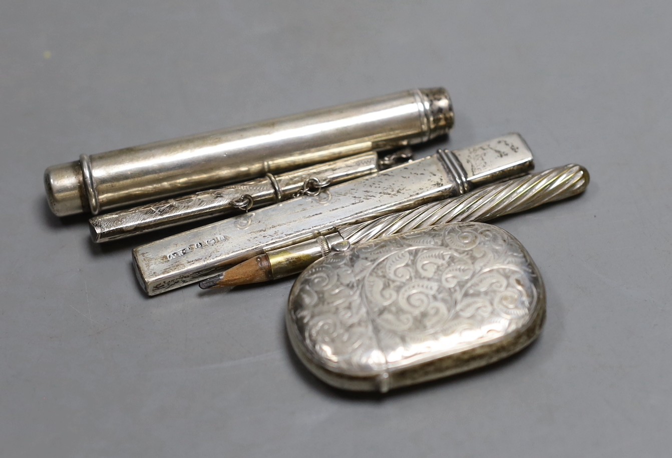 A silver vesta case, two silver pencil holders, one other plated holder and a white metal toothpick holder.